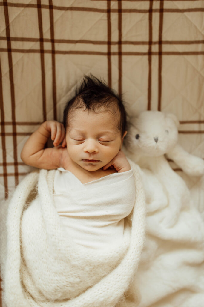 in home newborn session with baby sleeping next to a stuffie.